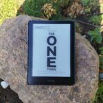 Das Buchcover von The ONE Thing von Gary Keller auf einem Kindle, der draußen auf einem großen Felsen liegt.