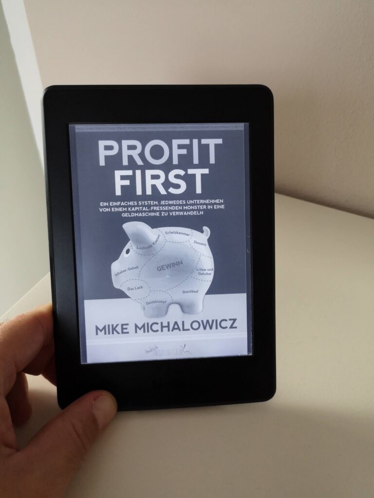 Das Buch Profit First in der Hand auf einem Kindle erkennbar